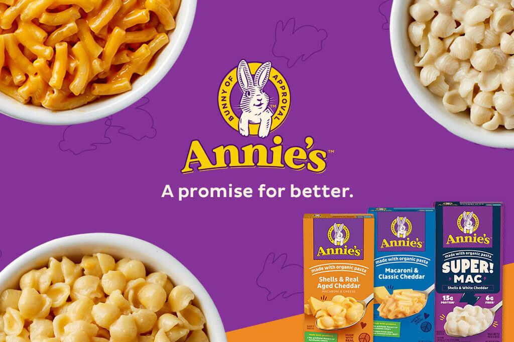 Three front facing pack shots of Macaroni Classic Cheddar, Real Aged Cheddar and Super Mac Shells White Cheddar in the bottom right corner on a purple & orange background with a bunny logo & text saying, "A promise for better". Three white bowls of White Shells Cheddar Mac & Cheese, Aged Cheddar Mac & Cheese and Classic Cheddar in on either side of the logo.