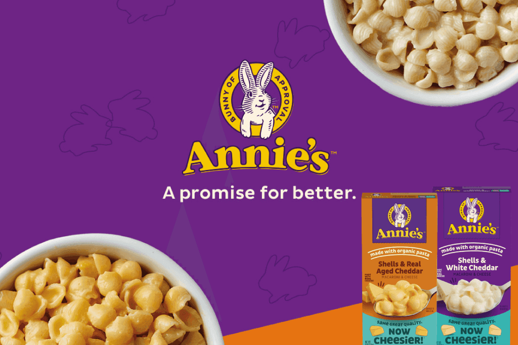 Three front facing pack shots of Macaroni Shells & Real Aged Cheddar and Shells White Cheddar in the bottom right corner on a purple & orange background with a bunny logo & text saying, "A promise for better".