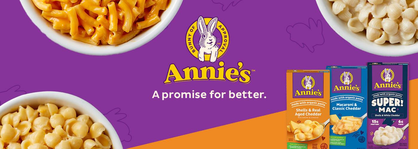 Three front facing pack shots of Macaroni Classic Cheddar, Real Aged Cheddar and Super Mac Shells White Cheddar in the bottom right corner on a purple & orange background with a bunny logo & text saying, "A promise for better". Three white bowls of White Shells Cheddar Mac & Cheese, Aged Cheddar Mac & Cheese and Classic Cheddar in on either side of the logo.