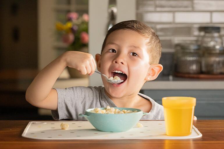 A child eating a bowl of Annie’s Mac & Cheese on a placemat.