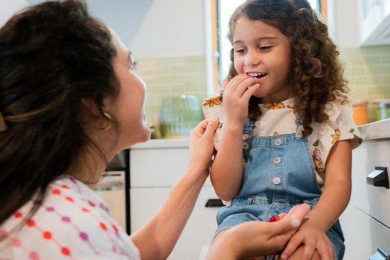 A child gazing down at a woman who is holding Annie's fruit snacks in her hand