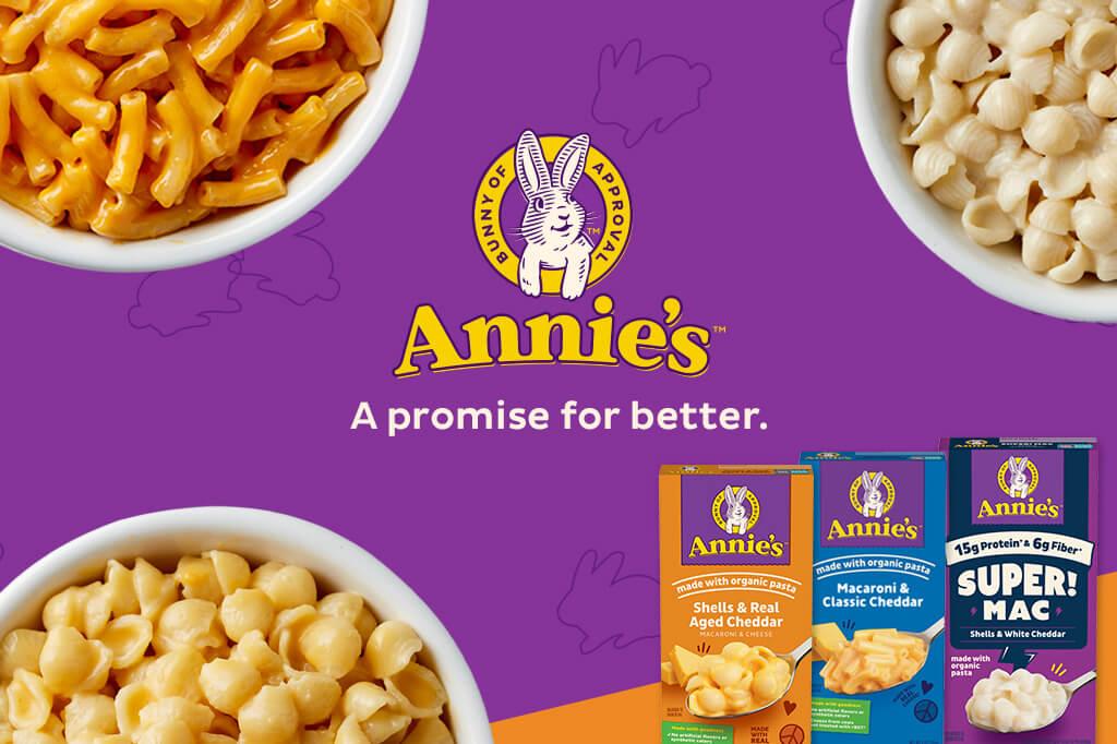 Three front facing pack shots of Macaroni Classic Cheddar, Real Aged Cheddar and Super Mac Shells White Cheddar in the bottom right corner on a purple & orange background with a bunny logo & text saying, "A promise for better". Three white bowls of White Shells Cheddar Mac & Cheese, Aged Cheddar Mac & Cheese and Classic Cheddar in on either side of the logo.