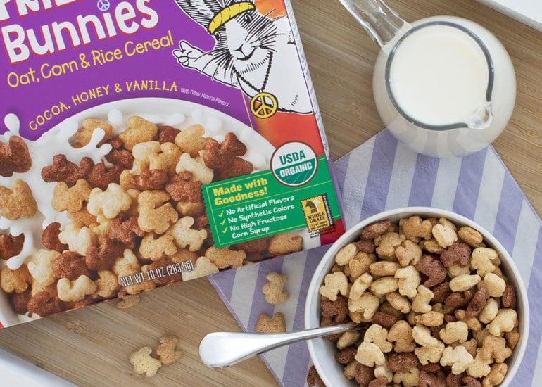 Bowl of Annie's cereal, pitcher of milk and the box of cereal. The box includes information about the USDA Organic standard.