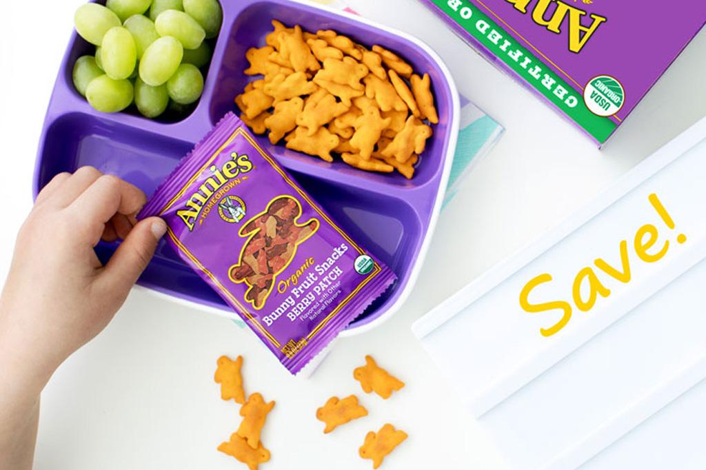 A Tiffin box containing grapes, bunny crackers and Annie's fruit snacks pouch