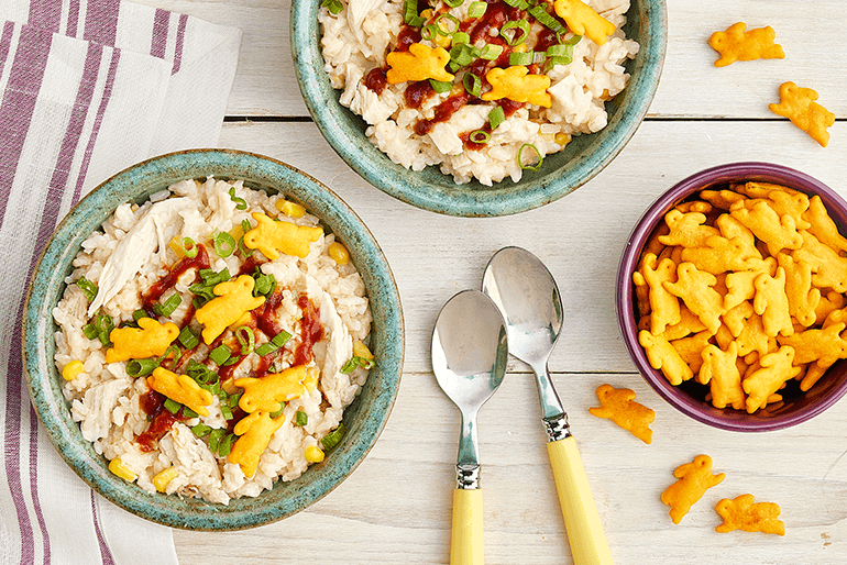 Two bowls of rice with cheese bunnies and chives on top with a bowl of the bunnies next to them
