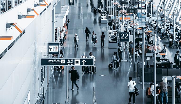 A photo of a busy airport with ticket stations, seating and bathroom sign.