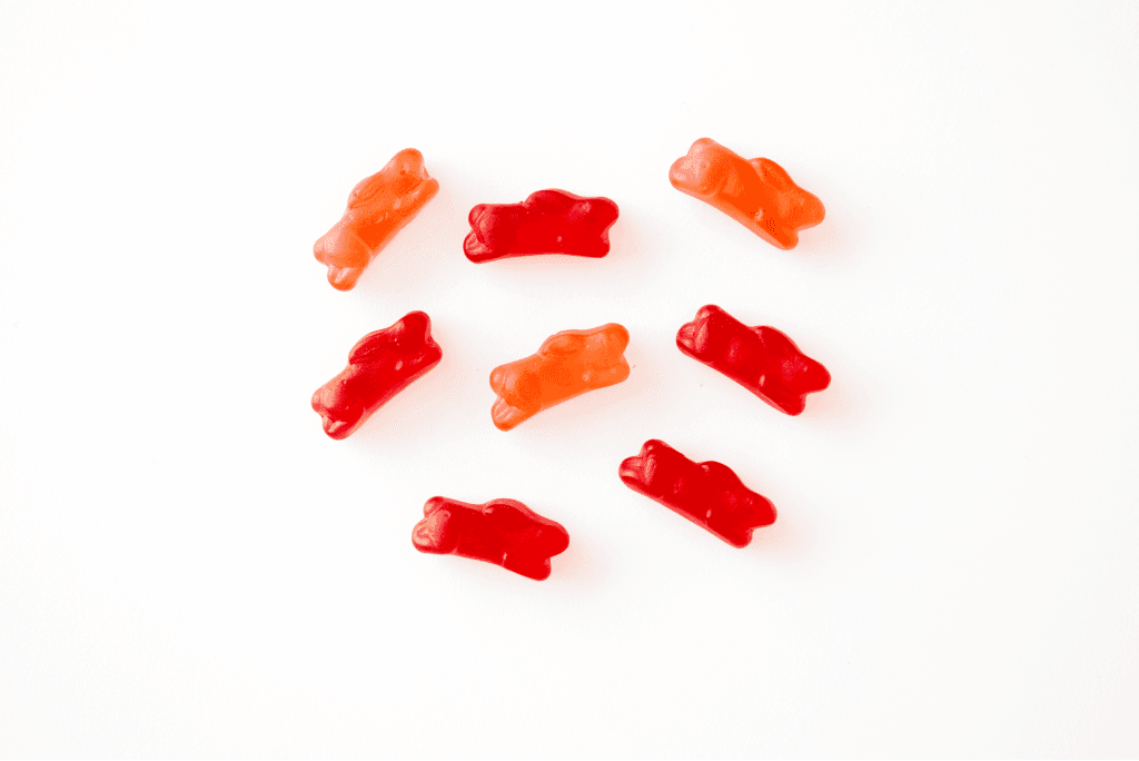Nine gummy bear candies arranged on a white surface.
